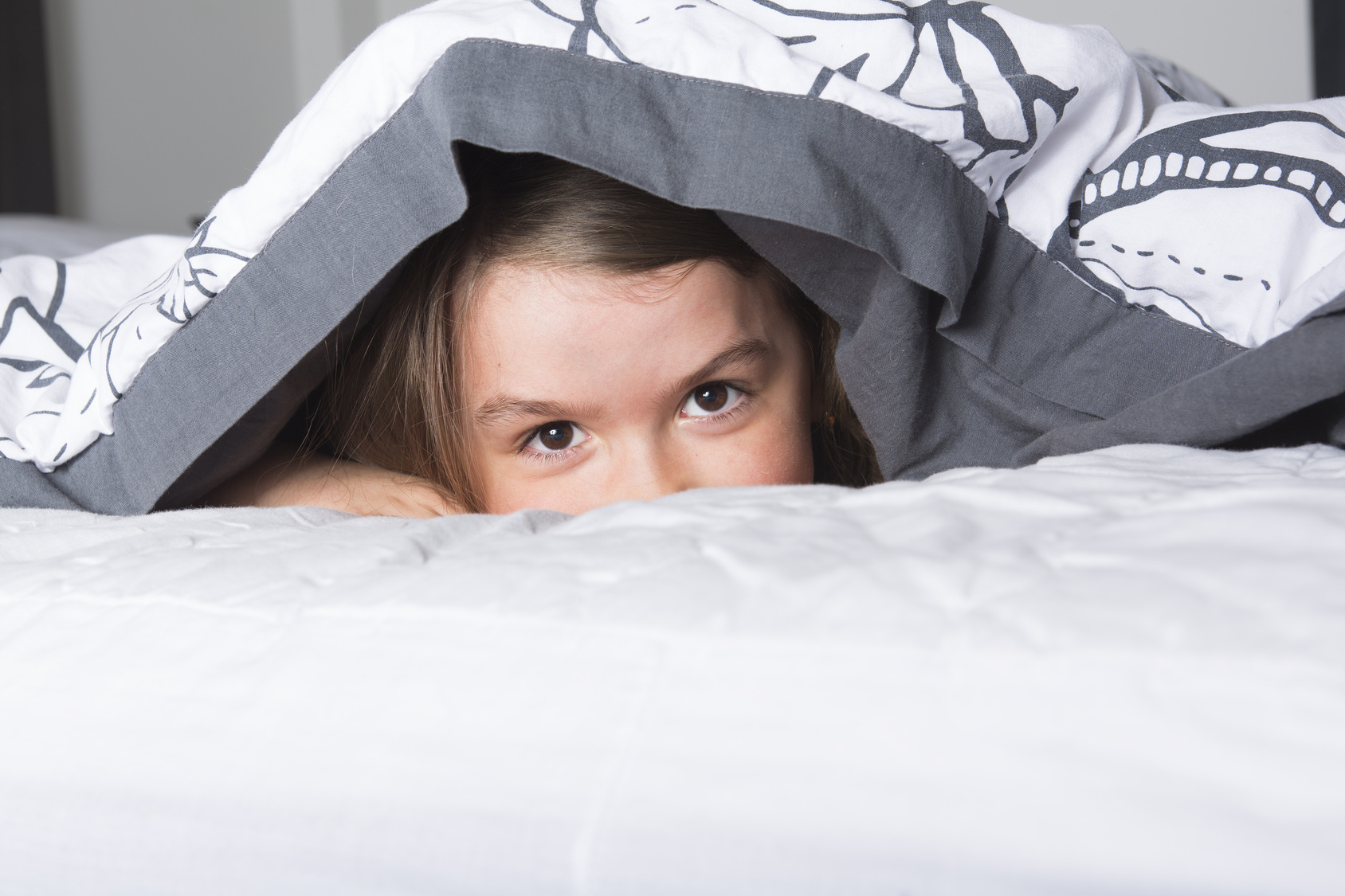 A Child or teen under covers in bed