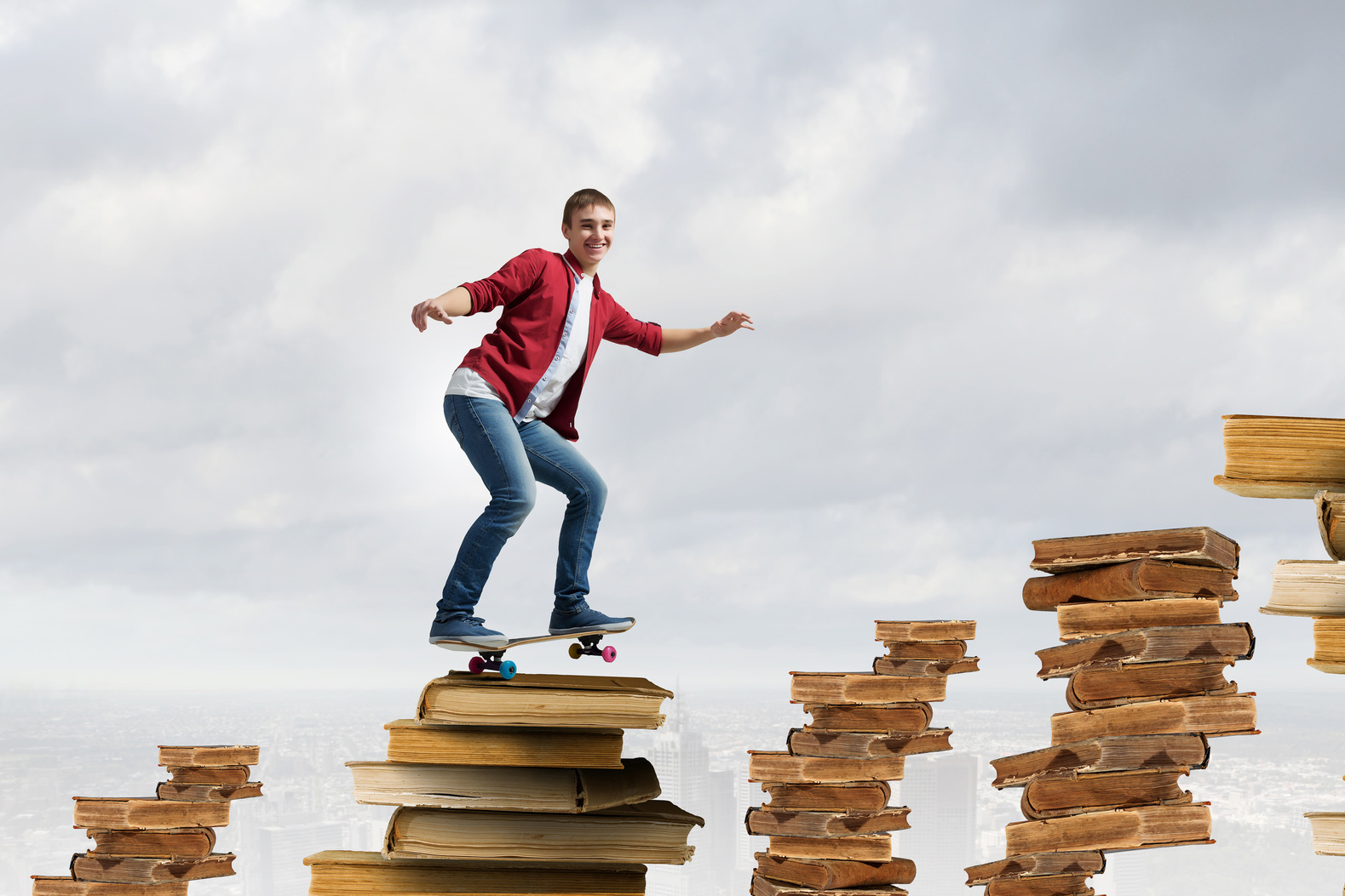 Handsome teenager acive boy riding skateboard on books