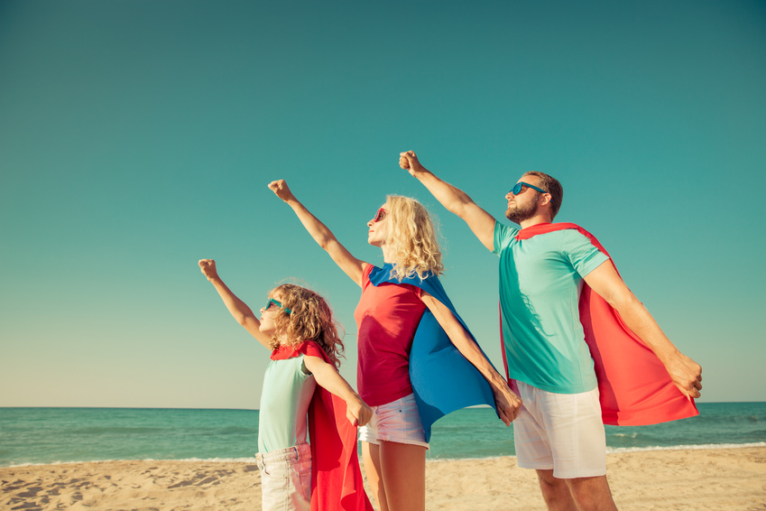 Family of superheroes on the beach. People having fun outdoor. Summer vacation concept