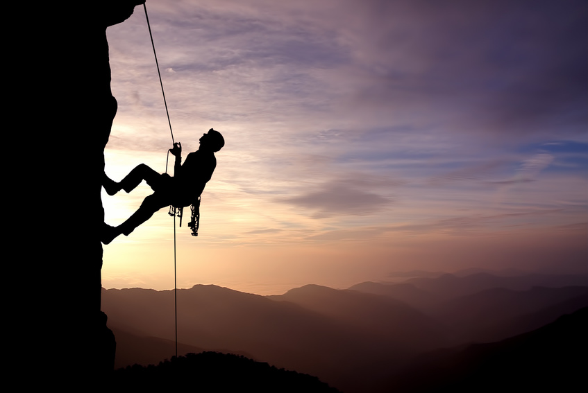 Silhouette of a climber on a vertical wall over beautiful sunset